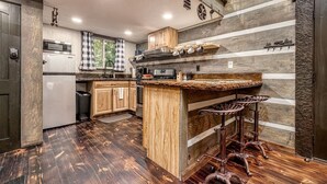 A kitchen with wooden cabinets, a built-in bar area, and a window with checkered curtains.