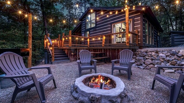 A cabin with a deck, outdoor seating, and a fire pit.