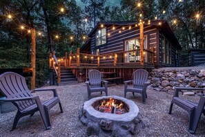 A cabin with a deck, outdoor seating, and a fire pit.