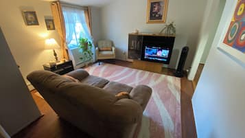 A living room with a sofa, a TV, a chair, a lamp, and a fireplace.