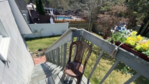 Une terrasse en bois avec une chaise, une piscine et un jardin fleuri.