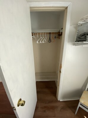 Un placard avec des vêtements suspendus et une étagère avec des vêtements pliés.