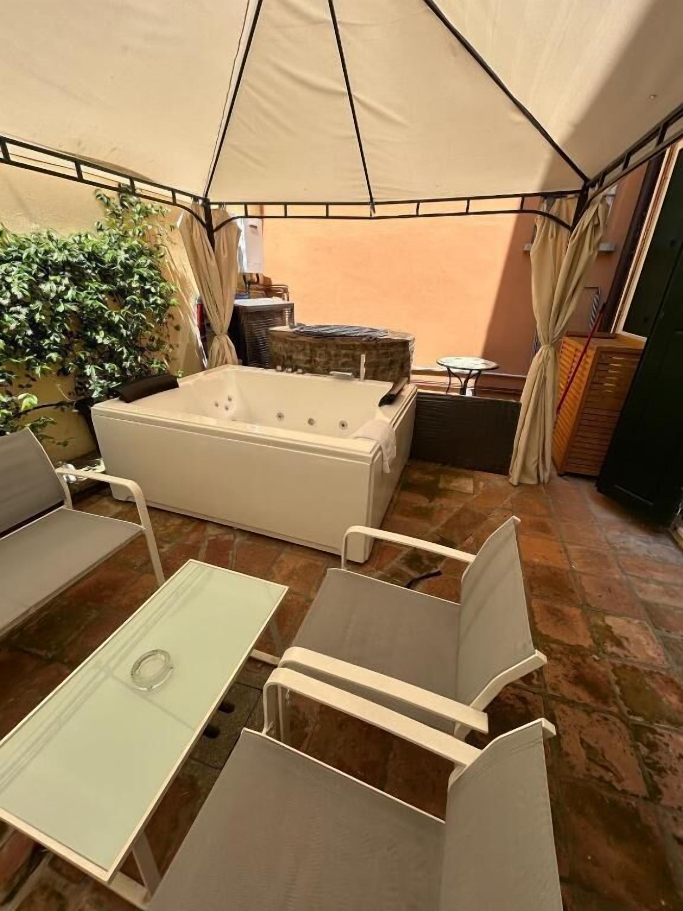 Un espace extérieur aménagé avec une tente, un jacuzzi, des chaises et une table.