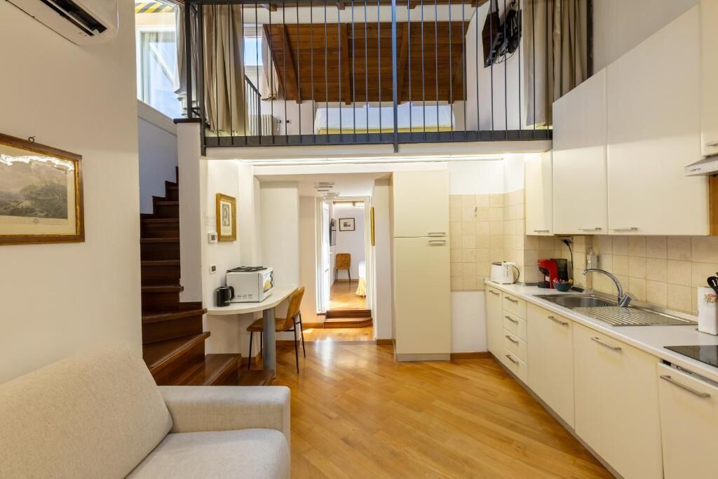 Une cuisine de taille réduite avec un coin repas, un plancher en bois et un escalier menant à un niveau supérieur.