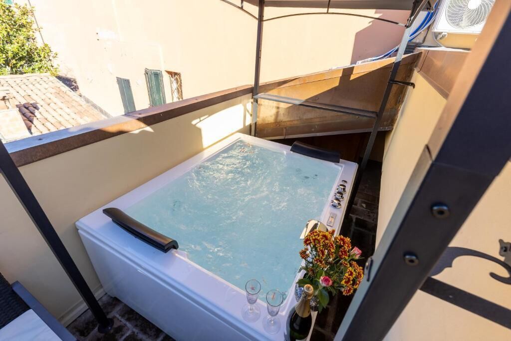 A hot tub with a glass enclosure, a bottle of champagne, and glasses on a balcony.