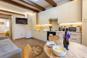 Una cocina moderna con armarios blancos, microondas integrado y un comedor con una mesa dispuesta para dos.