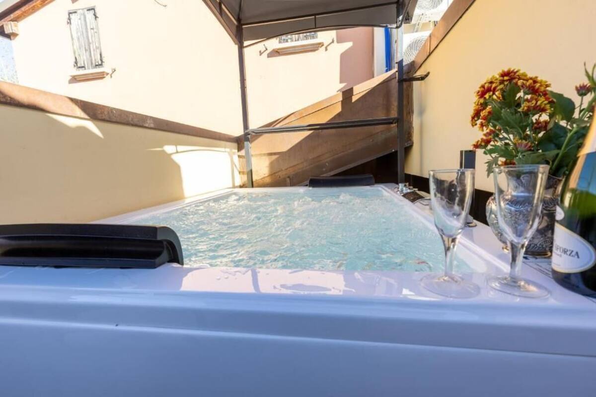 A hot tub with glasses and a bottle, a staircase, and a building in the background.