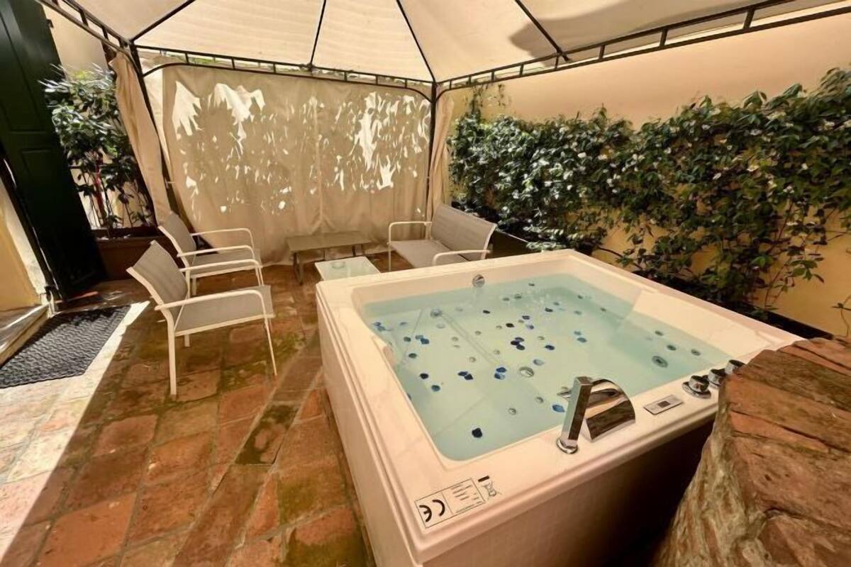 A spa area with a hot tub, two white chairs, and a wall covered with green plants.