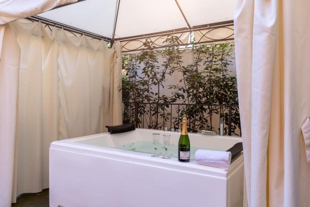 A private bathroom with a bathtub, a bottle of champagne, and two glasses.