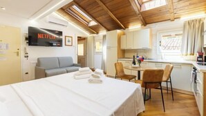 A cozy room with a bed, a TV mounted on the wall, a kitchenette, and a window with curtains. - Bolognaroomscom - Frassinago deluxe (Bologna)