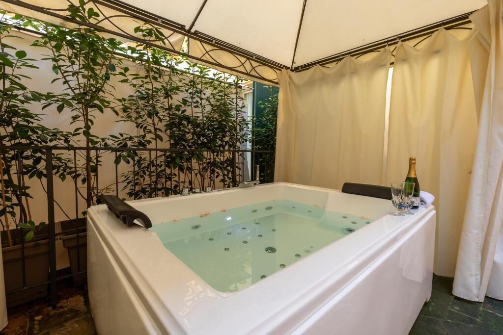 A spa area with a hot tub, a bottle of champagne, and potted plants.