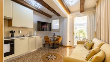 A modern kitchen with a dining area, a sofa, and a TV.