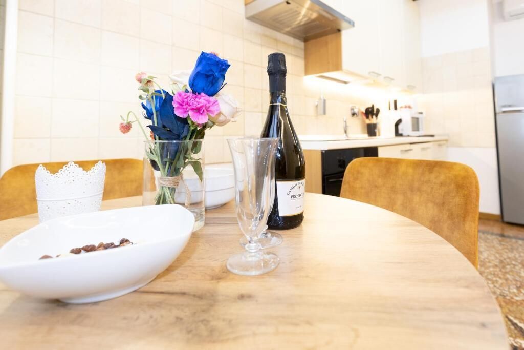 Una mesa de comedor con una botella de vino, una copa y un plato de comida en una habitación de hotel.