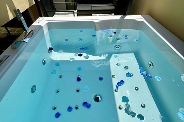 A hot tub with blue pebbles and a white lounge chair. - Bolognaroomscom - Frassinago deluxe (Bologna)