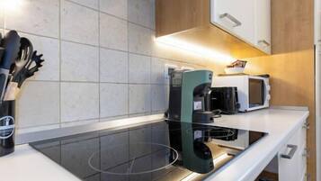 Une cuisine moderne équipée d’une plaque de cuisson à induction noire, d’un four à micro-ondes et d’une bouilloire.