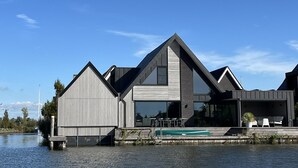 Ein modernes Haus mit einem großen Panoramafenster und einem Pool.