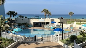 Un espace piscine avec des chaises longues et des parasols, un panneau indiquant « Vue panoramique sur le golfe », et une vue sur l’océan.