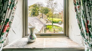 A window with a view of a garden and a building. - Cuckoo (Bakewell)