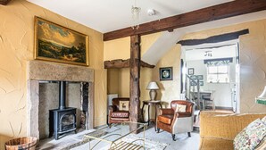 A cozy living room with a fireplace, leather armchairs, a sofa, and a dining area visible through an open doorway. - Cuckoo (Bakewell)