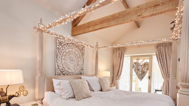 A spacious bedroom with a large bed, a canopy, and a view of the outdoors. - Love Nest (Bakewell)