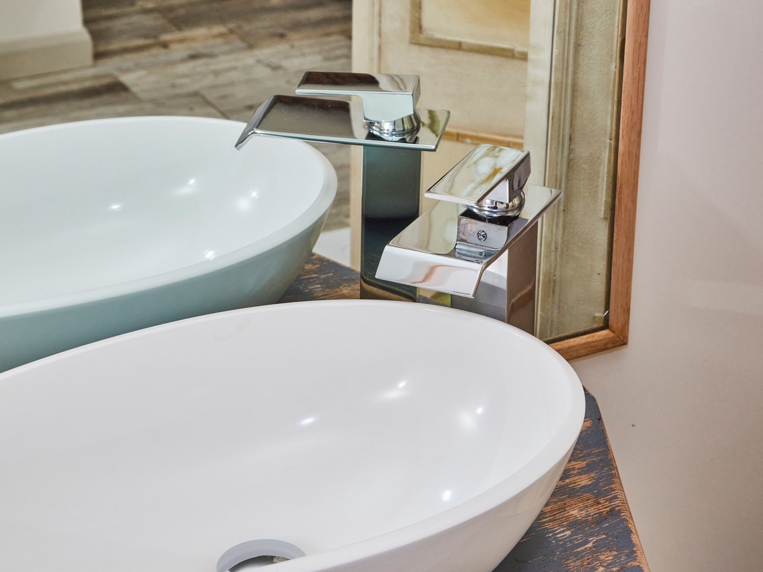 A bathroom with two sinks, one larger and one smaller, and a mirror above the smaller sink.
