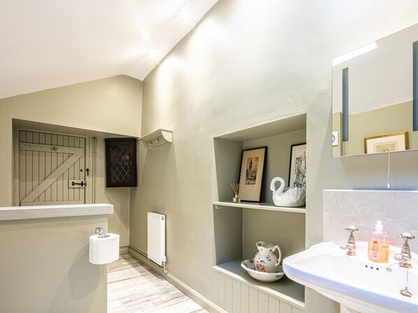 A bathroom with a toilet, sink, and shelves with decorative items.