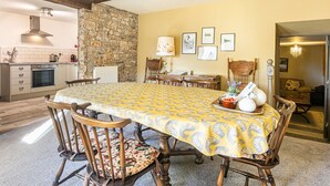 Un comedor con una mesa grande, sillas y una pared de piedra.
