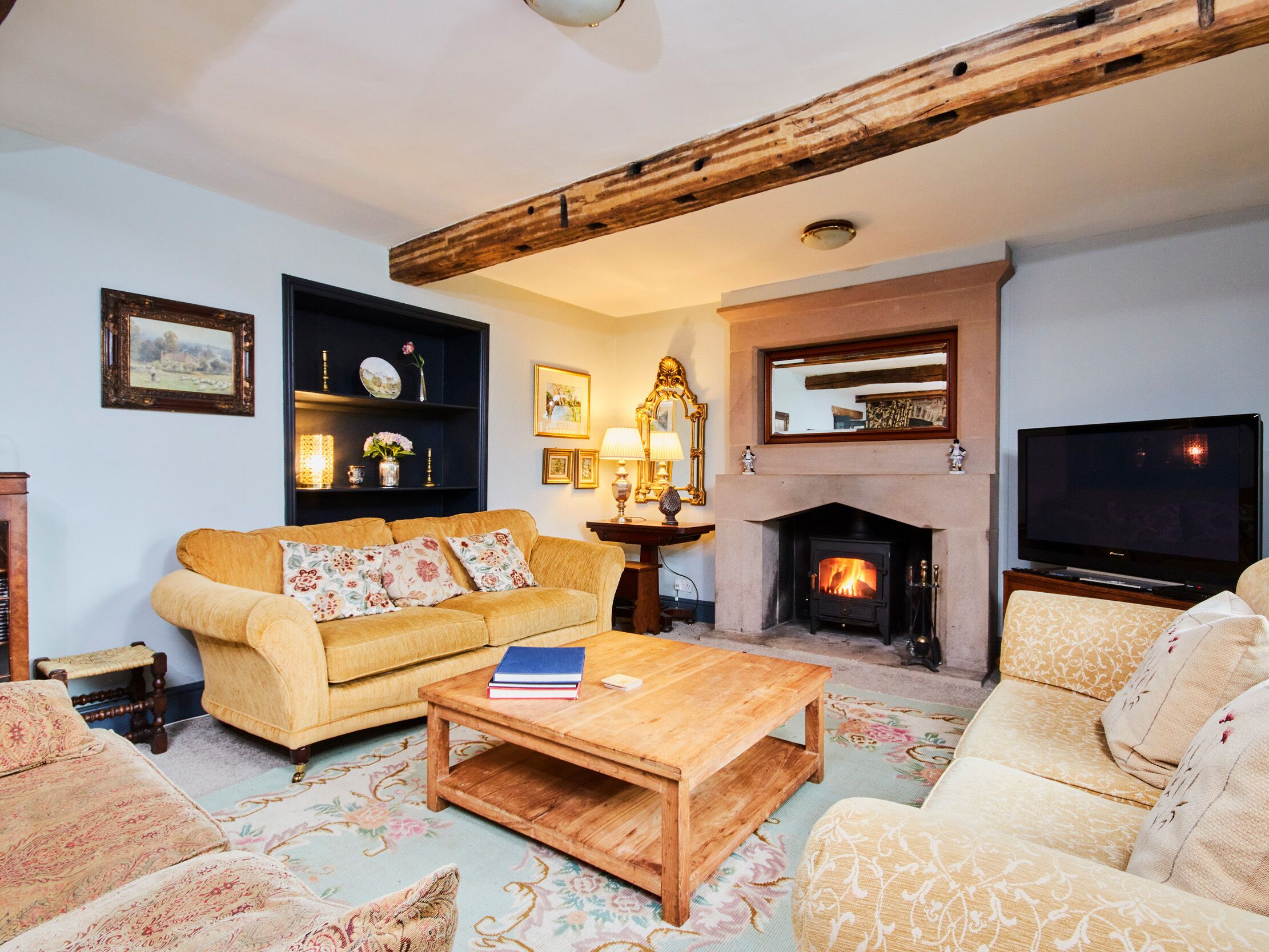 Una sala de estar acogedora con chimenea, un sofá, una mesa de centro y un televisor.