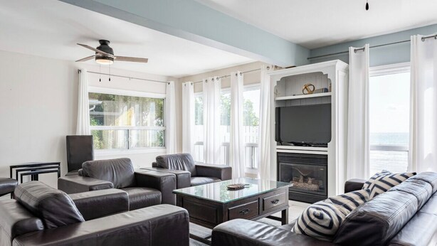 A modern living room with a fireplace, leather sofas, a glass coffee table, and a television. - Sunset Getaway on Long Beach (Wainfleet)