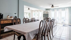 A dining area with a long table, chairs, a coffee maker, and a blender on a wooden cabinet. - Sunset Getaway on Long Beach (Wainfleet)