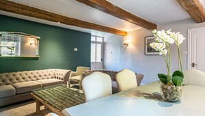 En hyggelig stue med en grøn væg, træbjælker, en sofasæt, et sofabord og en orkidé i potte.
