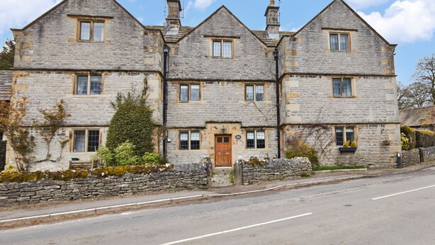 A stone building with a central entrance, multiple windows, and a stone wall in front. - The Dower House (Bakewell)