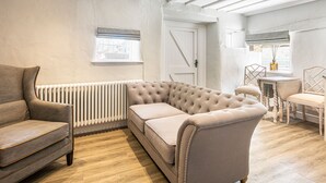 A modern living room with a sectional sofa, a radiator, and a dining area with a table and chairs. - The Artists Loft (Bakewell)