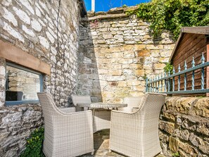 A stone-walled outdoor seating area with wicker furniture. - The Artists Loft (Bakewell)