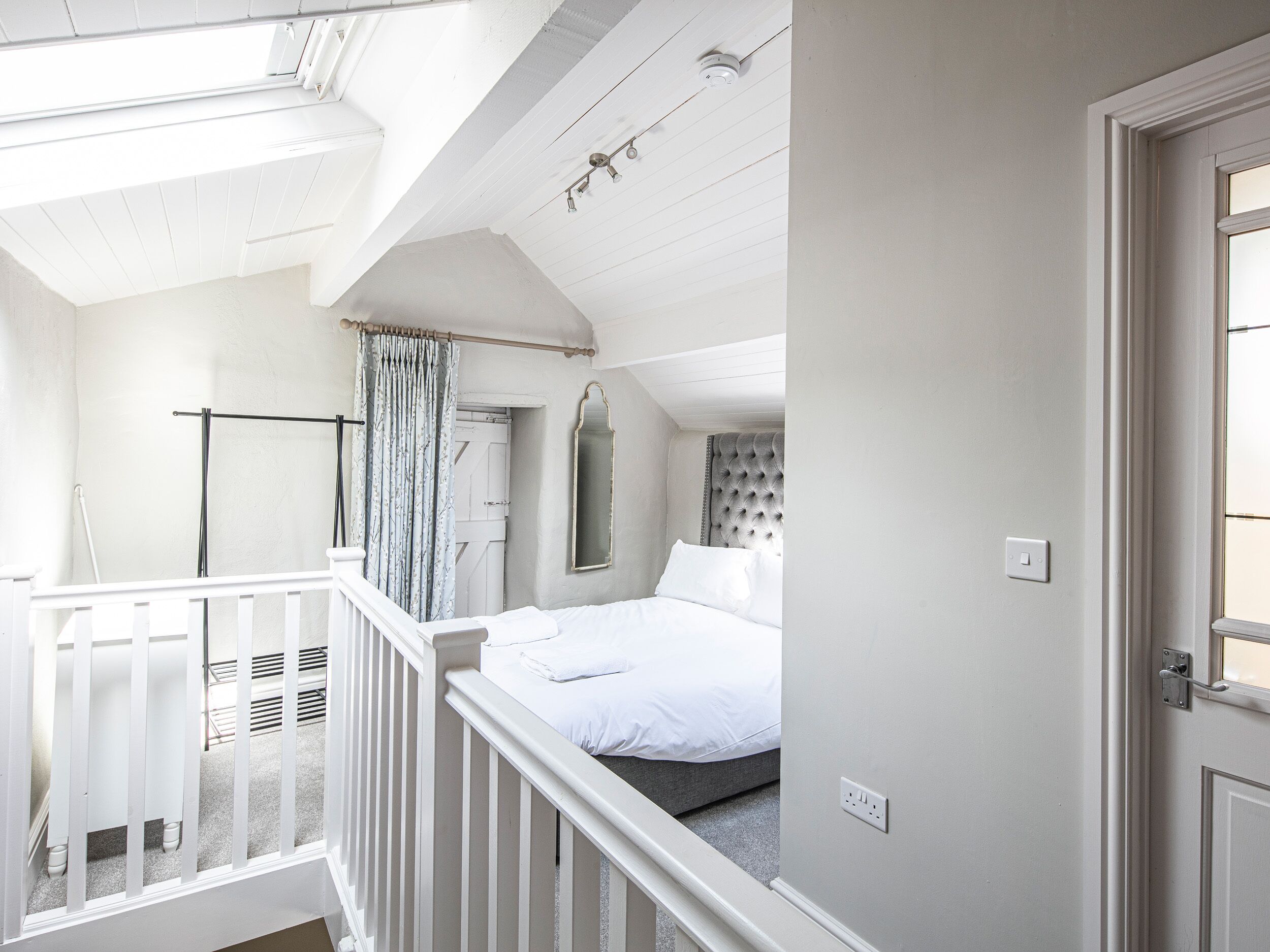 Une chambre à coucher avec un lit, une fenêtre, une porte et une balustrade de balcon.