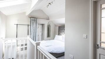 Une chambre à coucher avec un lit, une fenêtre, une porte et une balustrade de balcon.