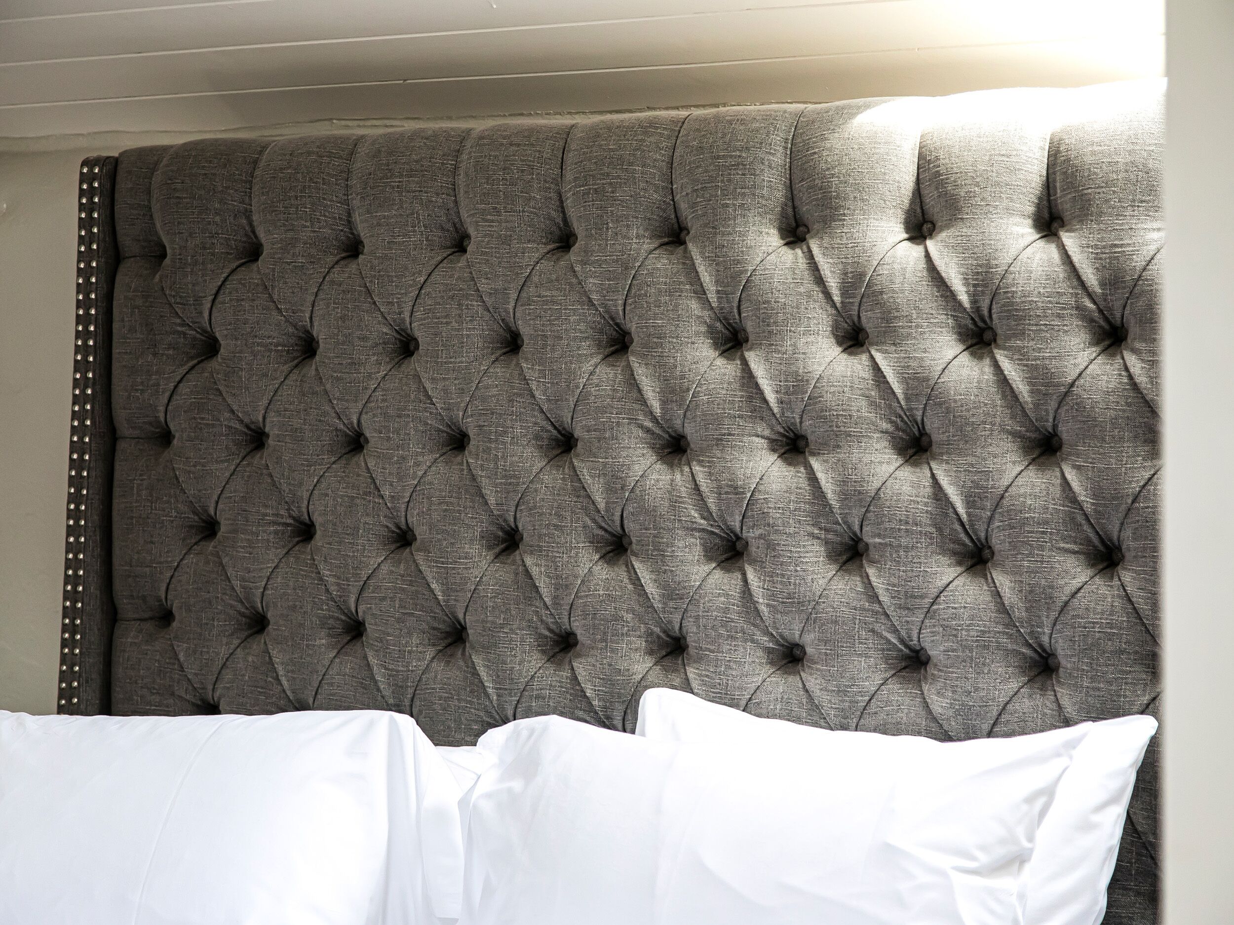 A tufted headboard with a buttoned design and a studded trim.