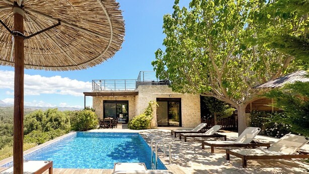 A modern outdoor pool area with lounge chairs and a thatched umbrella.