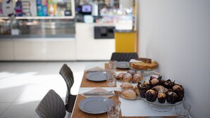Une table de petit-déjeuner dressée avec des assiettes, des verres et des viennoiseries.