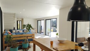 Una sala de estar moderna con una mesa de comedor de madera, un sofá azul y plantas en macetas.
