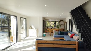 Una sala moderna con un banco de madera, un sofá azul y una escalera.