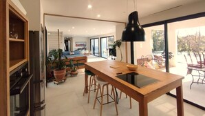 Una cocina moderna con una isla central, armarios de madera y una lámpara colgante negra.