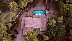 Vista aérea de una casa con piscina, rodeada de árboles.