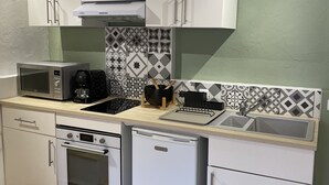 Uma cozinha compacta com armários brancos, micro-ondas, cafeteira, pia e lava-louças.