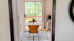 A doorway leading to a dining area with a round table and orange chairs, a ceiling light fixture, and a view of a balcony with a red railing. - Good Vibes House - Centrally located, cozy house!  (Springfield)