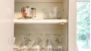 A kitchen cabinet with shelves holding a measuring cup, a mixing bowl, and several wine glasses. - Good Vibes House - Centrally located, cozy house!  (Springfield)