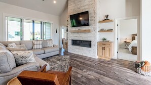 A spacious living room with a stone fireplace, a large flat-screen TV, and a comfortable seating area.