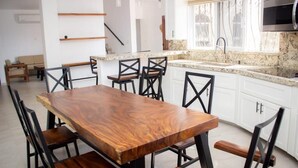 A modern kitchen with white cabinets, a granite countertop, and a wooden dining table with chairs. - Wonderful residence w/studio, 15 min walk distance from beach & restaurants! (Ixtapa Zihuatanejo)