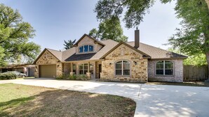 Une maison à deux étages avec une façade en pierre, un garage et une pelouse bien entretenue.