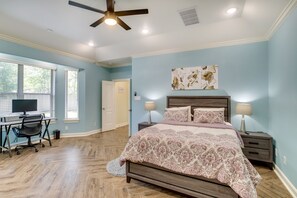 A bedroom with a bed, nightstands, a desk, and a chair.